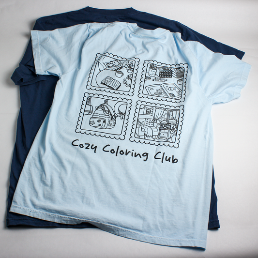 Light blue t-shirt with black illustrations and 'Cozy Coloring Club' text on a light gray background, Back View